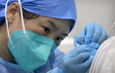 In this Jan. 15, 2021, file photo, a medical worker gives a coronavirus vaccine shot to a patient at a vaccination facility in Beijing.