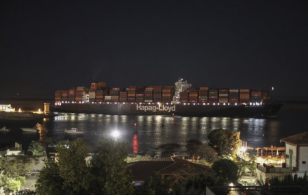 A cargo ship sails through the town of Suez, Egypt, Tuesday, March 30, 2021 as traffic resumed through the Suez canal after it was blocked by a massive ship that had been stuck sideways for n