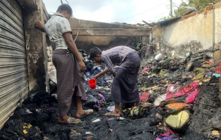 People inspect the debris after a fire in a makeshift market near a Rohingya refugee camp in Kutupalong, Bangladesh, Friday, April 2, 2021.