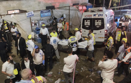 Israeli security officials and rescuers carry a body of a victim who died during a Lag Ba'Omer celebrations at Mt. Meron in northern Israel, Friday, April 30, 2021.