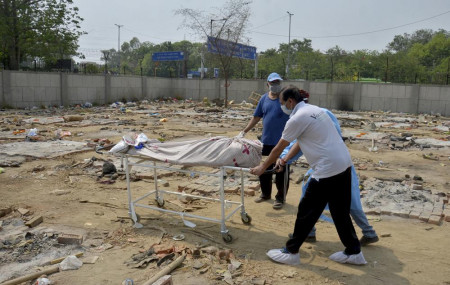 Body of a COVID-19 victim is wheeled in a ground that has been converted into a crematorium in New Delhi, India, Saturday, May 1, 2021.