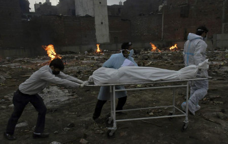 Body of a COVID-19 victim is wheeled in for cremation in a ground that has been converted into a crematorium in New Delhi, India, Thursday, May 6, 2021.