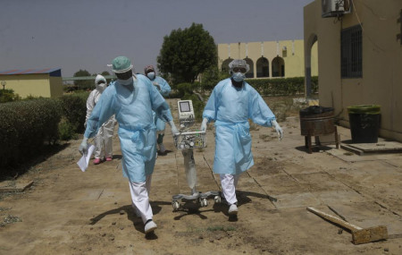 Doctors caring with COVID-19 patients ferry medical equipment, at the Farcha provincial hospital in N'Djamena, Chad, Friday April 30, 2021.