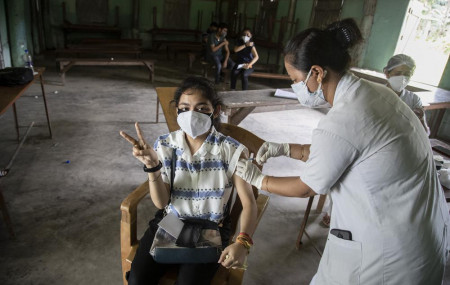 An Indian woman getting vaccinated with a dose of COVAXIN against the coronavirus gestures to camera in Gauhati, Assam, India, Monday, May 10, 2021.