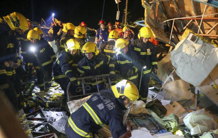 In this photo released by China's Xinhua News Agency, emergency personnel search through the wreckage of buildings destroyed by a reported tornado in Wuhan in central China's Hubei Province, 