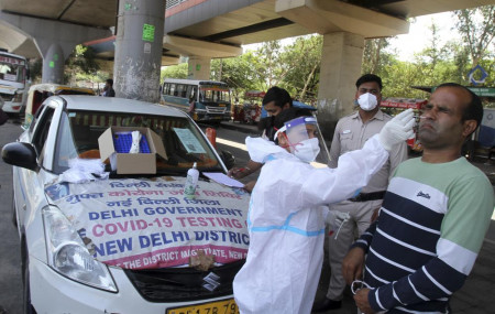 A man reacts as a health worker in protective suit takes his nasal swab sample to test for COVID-19 in New Delhi, India, Saturday, May 22, 2021.