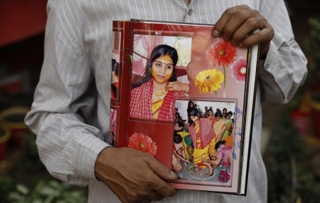 Radha Gobindo Pramanik holds photographs of his daughter who died of COVID-19 in Lucknow, India, Thursday, June 3, 2021.