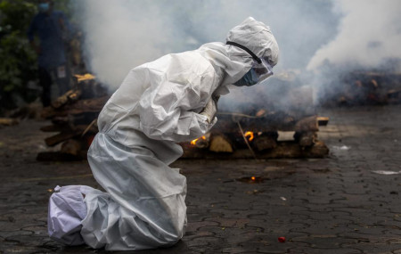 In this July 2, 2021, file photo, a woman breaks down as she prays before the cremation of a relative who died of COVID-19 in Gauhati, India.