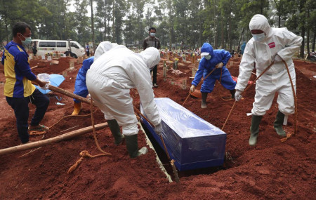 Workers in protective gear lower a coffin of a COVID-19 victim to a grave for burial at the Cipenjo Cemetery in Bogor, West Java, Indonesia, Wednesday, July 14, 2021.