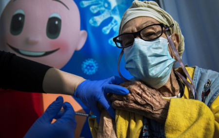 In this Tuesday, Jan. 5, 2021. file photo, a woman receives a coronavirus vaccine from medical staff at a COVID-19 vaccination center in Tel Aviv, Israel.