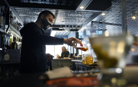 In this April 6, 2021, file photo, bartender Denis Angelov pours drinks at Tin Pan Alley restaurant in Provincetown, Massachusetts.