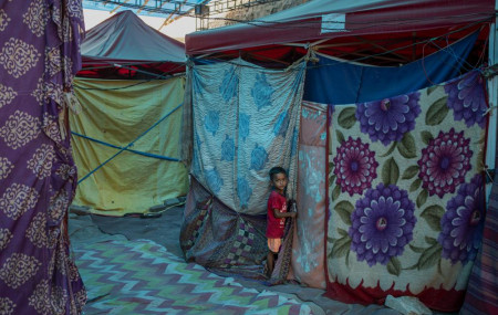 A young Rohingya refugee boy stands outside a tent at a refugee camp alongside the banks of the Yamuna River in the southeastern borders of New Delhi, sprawling Indian capital, July 1, 2021.