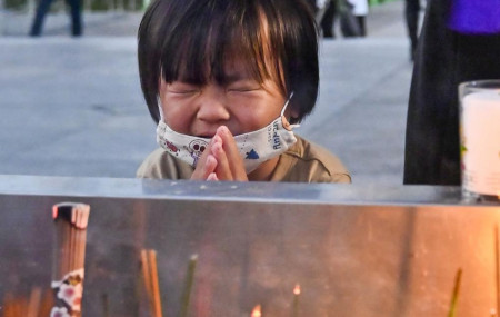 A child prays in front of the cenotaph dedicated to the victims of the atomic bombing at the Hiroshima Peace Memorial Park in Hiroshima, western Japan Friday, Aug. 6, 2021.