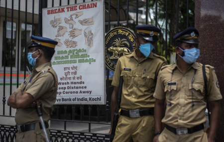 Police personnel wearing masks guard outside the Reserve Bank of India during a protest against the federal government's plan to privatize government assets in Kochi, Kerala state, India, Tue