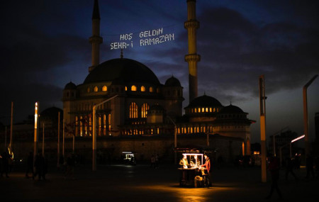 People buy roasted chestnuts next to Taksim mosque as the sun sets during the first day of the Muslim holy fasting month of Ramadan, in Istanbul, Turkey, Saturday, April 2, 2022.