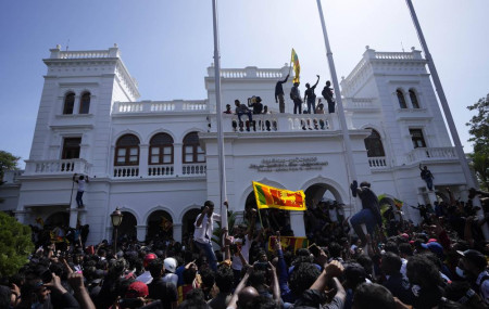 A protester, carrying national flag, stands with others on top of the building of Sri Lankan Prime Minister Ranil Wickremesinghe's office in Colombo, Sri Lanka, Wednesday, July 13, 2022. AP/R