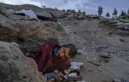 An Afghan drug addict smokes heroin on the edge of a hill in the city of Kabul, Afghanistan,Tuesday, June 7, 2022. (AP Photo/Ebrahim Noroozi/RSS)