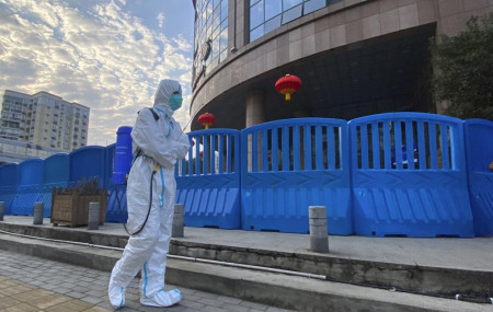 FILE - A worker in protective overalls and carrying disinfecting equipment walks outside the Wuhan Central Hospital, China on Feb 6, 2021. (AP Photo/RSS)