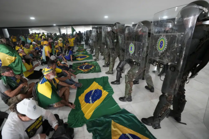 Protesters, supporters of Brazil's former President Jair Bolsonaro, sit in front of police after inside Planalto Palace after storming it, in Brasilia, Brazil, Sunday, Jan. 8, 2023. AP/RSS Photo