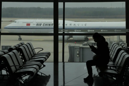 A passenger checks her phone as an Air China passenger jet taxi past at the Beijing Capital International airport in Beijing, Saturday, Oct. 29, 2022. AP/RSS Photo