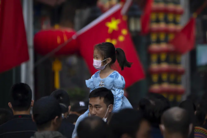 FILE - A girl wearing a face mask rides on a man's shoulders as they walk along a tourist shopping street in Beijing on Oct. 7, 2022. China has announced its first overall population decline in recent years amid an aging society and plunging birthrate. AP/RSS Photo