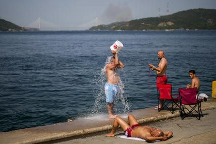FILE - People cool off at the Bosphorus as forest fire smoke rises, background, during a hot summer day in Istanbul, Turkey, July 26, 2023. Scientists say by far the biggest cause of the recent extreme warming is human-caused climate change and a natural El Nino. But some say there’s got to be something more. AP/RSS Photo