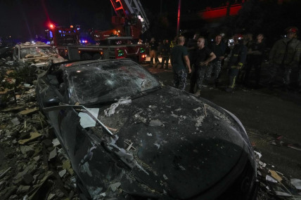 Policemen and civil defense workers inspect a damaged car near a building that was hit in an Israeli airstrike, in Beirut, Lebanon, early Monday, Sept. 30, 2024. (AP Photo)