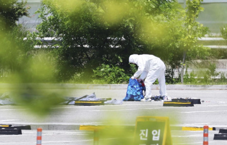 An officer wearing protective gear collects the trash from a balloon presumably sent by North Korea, in Siheung, South Korea, Sunday, June 2, 2024. (AP)