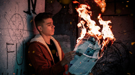 A man holds a burning newspaper. A man holds a burning newspaper. Photo by Arvin Latifi for Pexels.