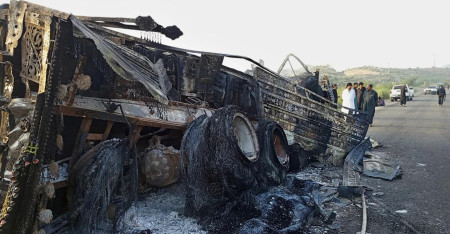 People look at a burnt vehicle which was torched by gunmen after they killed passengers at a highway in Musakhail, a district in Baluchistan province in restive southwestern Pakistan, Monday, Aug. 26, 2024. (AP Photo)