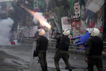 A riot police officer fires tear gas to disperse supporters of former Prime Minister Imran Khan during clashes outside Khan's residence, in Lahore, Pakistan, Tuesday, March 14, 2023. (AP/RSS Photo)