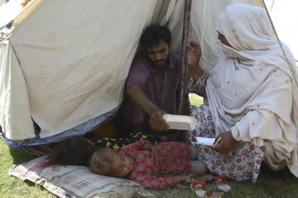 Rubina Bibi, 53, right, sit near to her family after take refuge at a camp after fleeing her flood-hit homes, in Charsadda, Pakistan, Tuesday, Aug. 30, 2022. AP/RSS Photo
