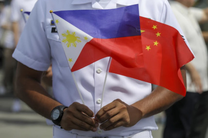 FILE - A member of the Philippine Coast Guard holds flags during the arrival of Chinese naval training ship, Qi Jiguang, for a goodwill visit at Manila’s port, Philippines, June 14, 2023. AP/RSS Photo