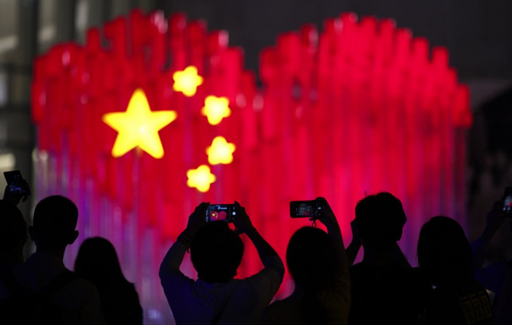 Visitors take photos with their smart phones of an installation depicting a heart shape Chinese national flag in Shanghai, China, Friday, Sept. 27, 2019. China will mark its 70th anniversary 