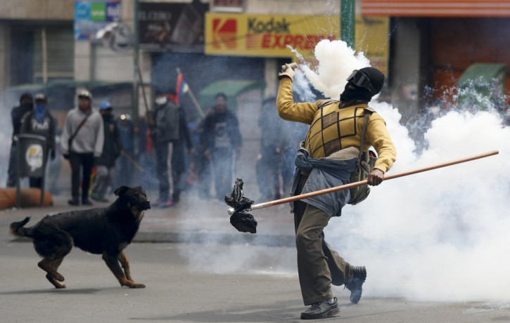 A backer of former President Evo Morales returns a tear gas canister to police during clashes in La Paz, Bolivia, Wednesday, Nov. 13, 2019.