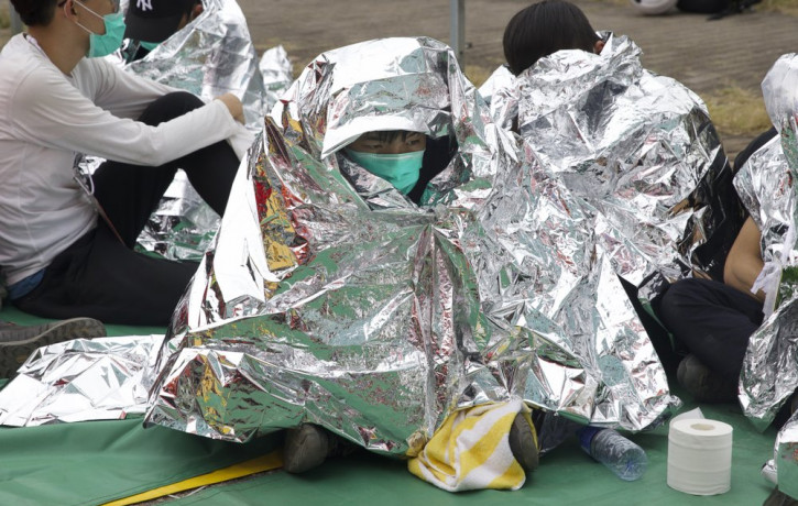 An injured youth sits under a space blanket at a casualty evacuation point near Hong Kong Polytechnic University in Hong Kong, Tuesday, Nov. 19, 2019.