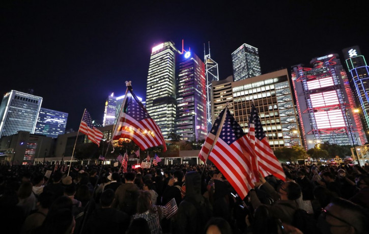 Protester holds U.S. flags during a demonstration in Hong Kong, Thursday, Nov. 28, 2019.