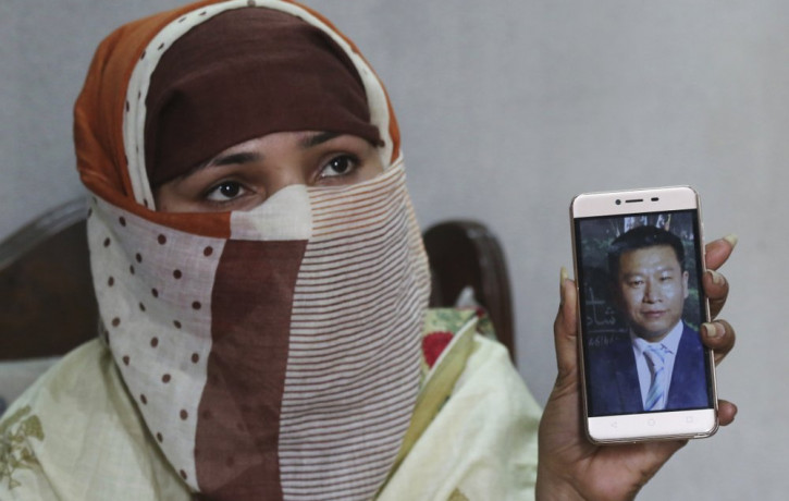 In this May 22, 2019 file photo, Sumaira a Pakistani woman, shows a picture of her Chinese husband in Gujranwala, Pakistan.
