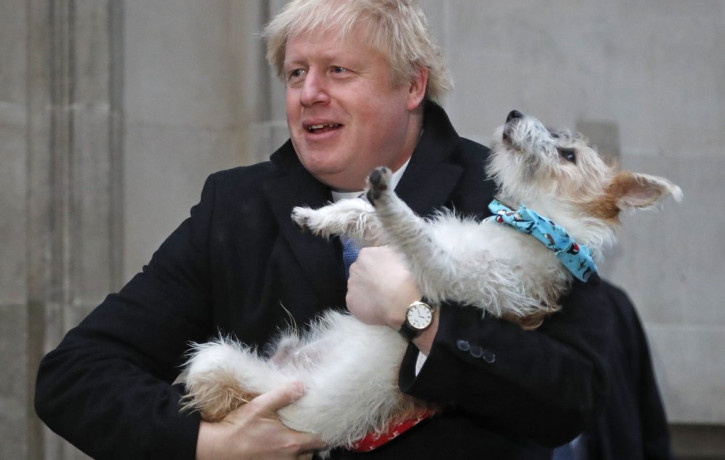 Britain's Prime Minister and Conservative Party leader Boris Johnson holds his dog Dilyn as he leaves after voting in the general election at Methodist Central Hall, Westminster, London, Thur