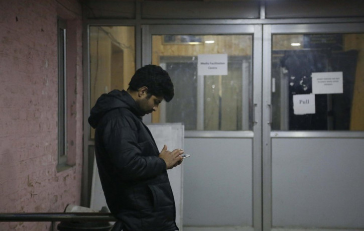 A man checks his cellphone outside a media facilitation centre in Srinagar, Indian controlled Kashmir, Tuesday, Dec. 31, 2019.