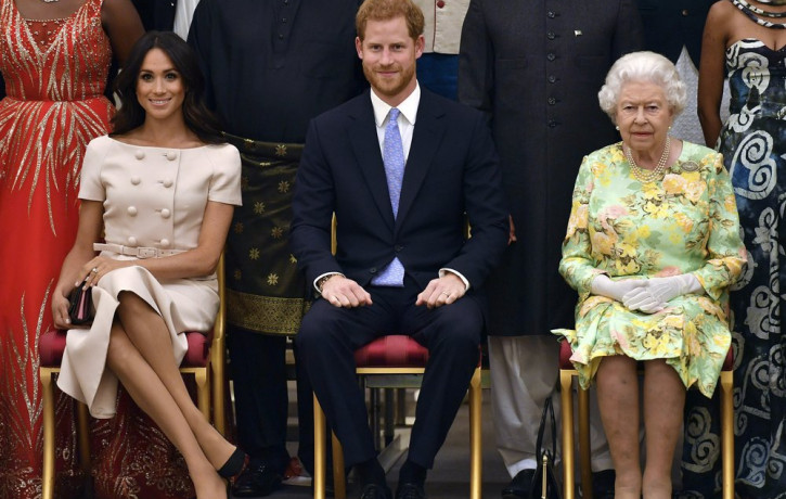 In this Tuesday, June 26, 2018 file photo Britain's Queen Elizabeth, Prince Harry and Meghan, Duchess of Sussex pose for a group photo at the Queen's Young Leaders Awards Ceremony at Buckingh