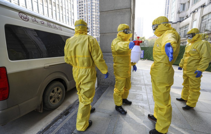 In this Jan. 30, 2020 file photo, funeral workers disinfect themselves after handling a virus victim in Wuhan in central China's Hubei Province, Thursday, Jan. 30, 2020.
