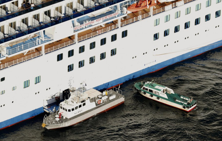 Japan Coast Guard's patrol boat, left, is brought alongside the cruise ship Diamond Princess to take passengers tested positive for coronavirus to hospitals off Yokohama, south of Tokyo, Wedn