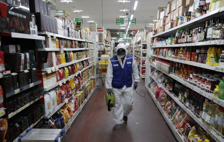 A worker wearing a protective suit sprays disinfectant as a precaution against the COVID-19 at a market in Seoul, South Korea, Thursday, Feb. 27, 2020.