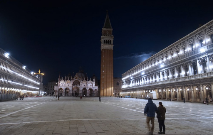 People walk in an almost empty St. Mark's Square in Venice, Italy, Monday, March 9, 2020.