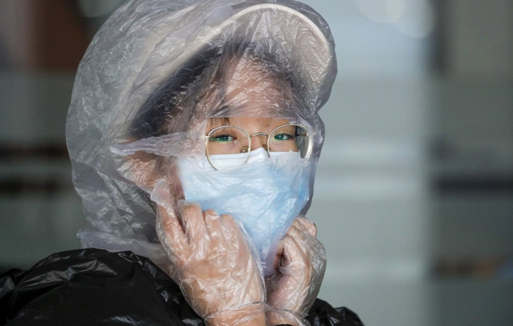 A Chinese woman uses a plastic bag to cover her head while waiting for her flight at the departure area of Manila's International Airport, Philippines on Wednesday, March 18, 2020.