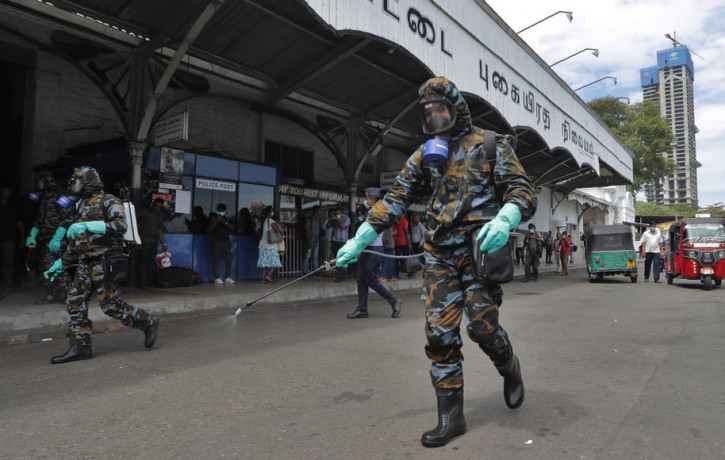 Sri Lankan government soldiers in protective clothes spray disinfectants at a railway station in Colombo, Sri Lanka, Wednesday, March 18, 2020.