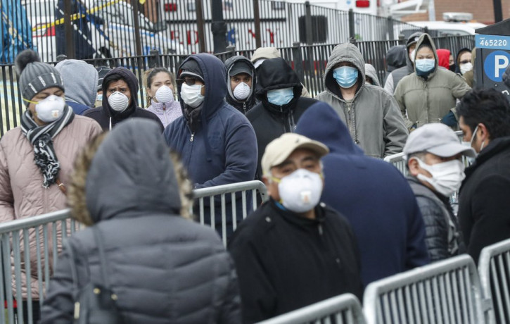 Patients wear personal protective equipment while maintaining social distancing as they wait in line for a COVID-19 test at Elmhurst Hospital Center, Wednesday, March 25, 2020, in New York.