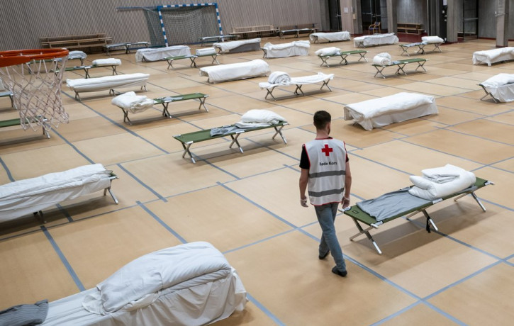 A Red Cross volunteer looks at beds set up for homeless people in the gymnasium of Uranienborg school, which is closed due to the corona eruption, in Oslo, Thursday, March 26, 2020.