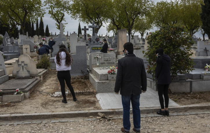 Relatives wearing face masks to protect against coronavirus, observe social distancing guidelines during a burial at a Madrid cemetery during the coronavirus outbreak in Madrid, Spain, Friday